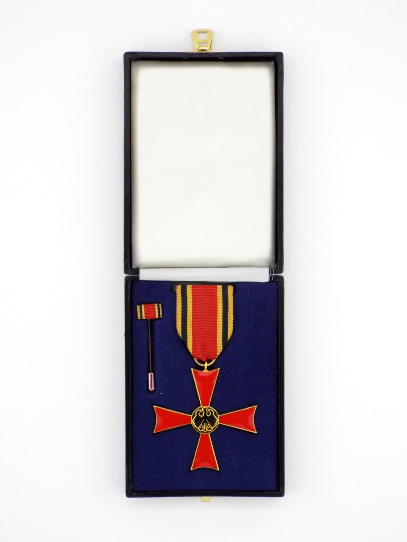 German Cold War Medal Federal Cross of Merit By STEINHAUER & LUCK in Presentation Case: Gilt framed Maltese cross medal features pristine, translucent red enamel arms centering a finely detailed, black finished federal eagle medallion. Reverse exhibits uniform factory frosting with crisp