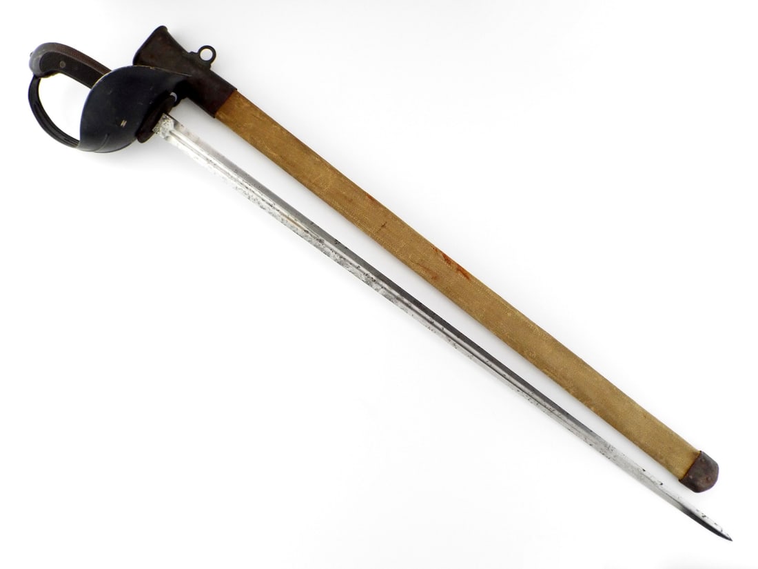 US WWI Patton Cavalry Sword By LANDERS FRARY & CLARK with Canvas Covered Scabbard: Straight, double edged thrusting blade presents uniform gray oxidation, crisp fuller and legible ricasso markings reading U.S. over ordnance insignia and L.F.&C. 1918. Darkened sheet steel basket guar