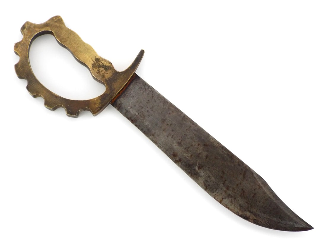 Brutal Australian WWII Combat Knuckle Knife Cog D-Guard Hilt: Broad Bowie style clip point steel blade shows dark age patina, surface oxidation and honest field wear. Sand cast brass D-guard knuckle handle with integral cog wheel projections cast directly onto t