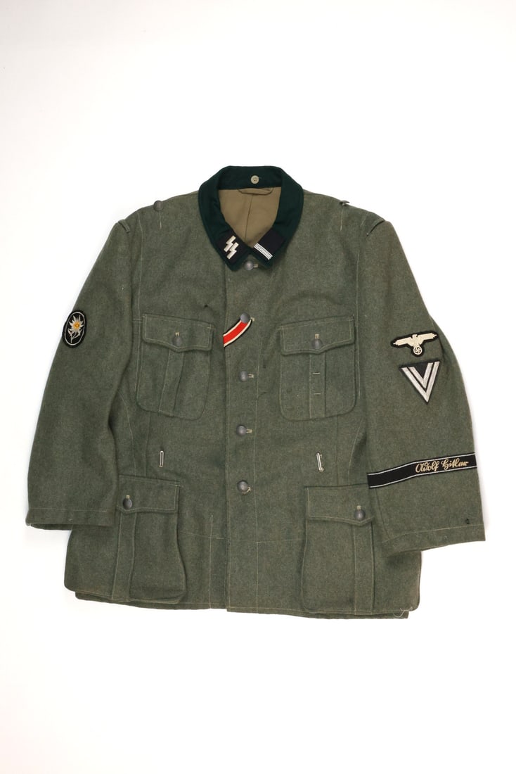 German Post WWII NCO Tunic 1st SS PANZER DIVISION Insignia: German Post WWII Tunic Waffen-SS leader division insignia. Blouse constructed of field grey wool showing minimal wear. Left sleeve displays machine embroidered eagle over a junior rank chevron and a b