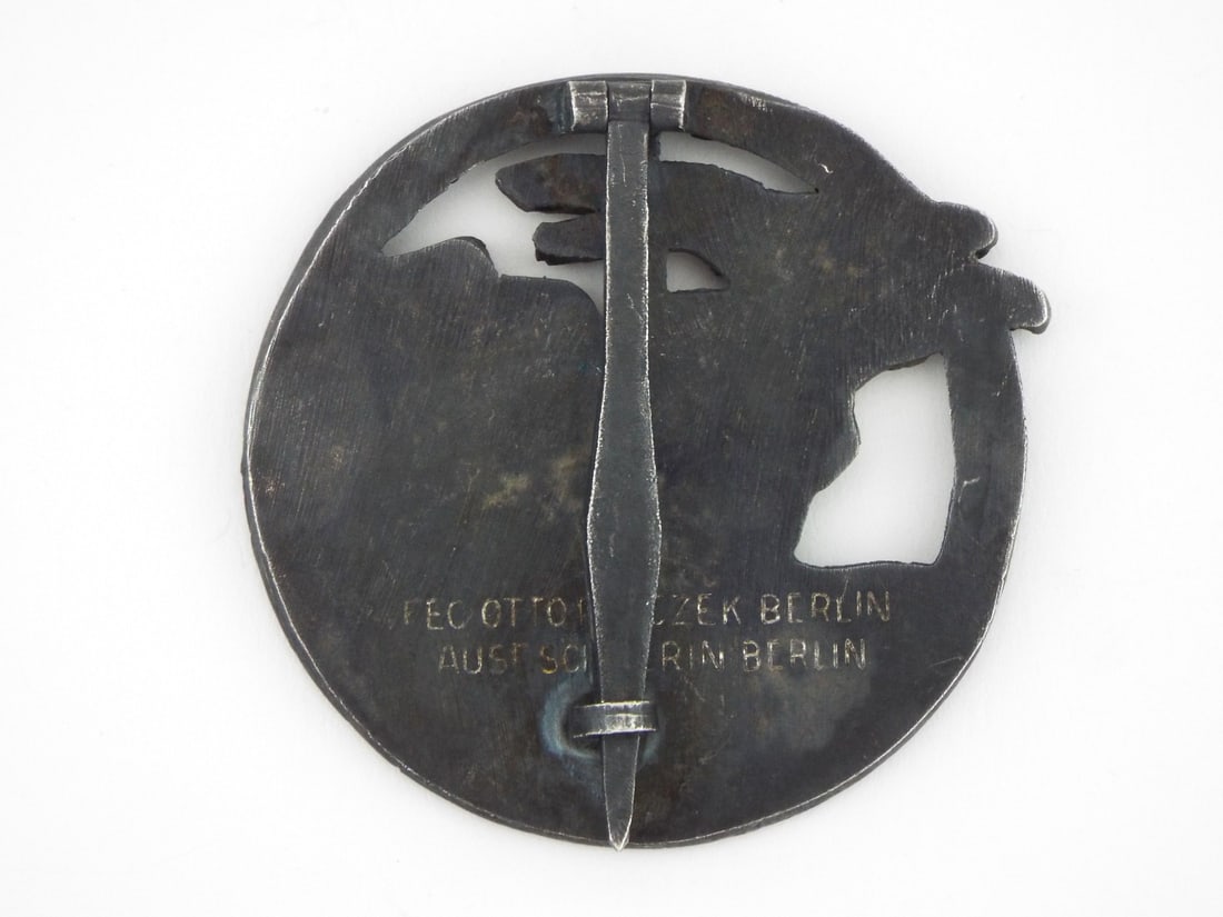 German WWII Blockade Runner Badge By SCHWERIN BERLIN Designed by Otto Placzek: Die struck zinc award badge retains most of its dark, toned finish on the reverse, showing honest wear to the raised highlights on the obverse ship and eagle. A solid, uncleaned patina rests in the re
