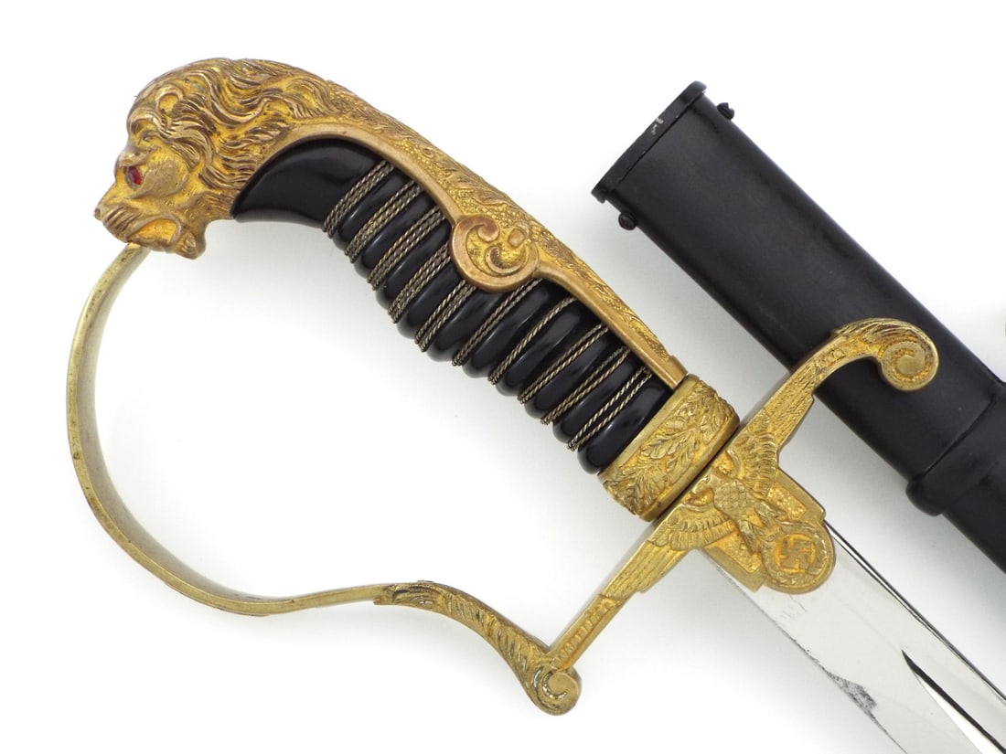 Private Purchase German WWII Officer Sword By RUDOLF BUCHEL Lion Head & Glass Eyes: Nickled steel blade features minor runner wear, light surface scratching and a clear ricasso stamped with the Rudolf Buchel, Solingen Merscheid maker logo. Cast brass hilt retains strong gilding with 