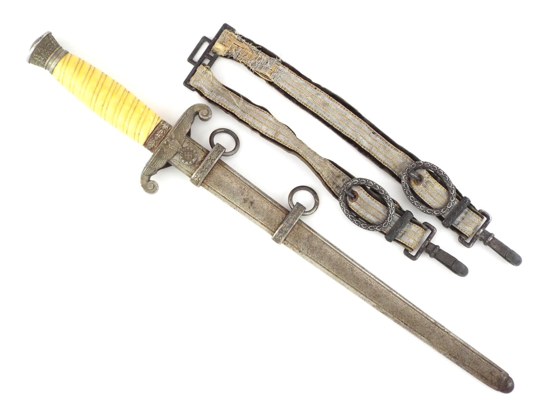 German WWII HEER OFFICER DAGGER with Rare Deluxe Hangers: Blade exhibits graying and localized oxidation spots. Crossguard and oak leaf pommel show heavy patina with silver loss to base metal. Yellow celluloid grip remains intact with standard diagonal ribbi
