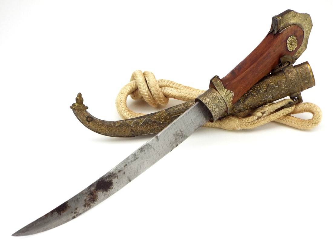 Antique Islamic Arabic Arab Moroccan Kouya A Dagger Knife in Ornate Mounts: Moroccan Koummya Dagger. Curved, single edged blade features a false edge and exhibits some runner marks from the scabbard. The hilt has an engraved brass and silver ferrule, a wooden grip with a silv