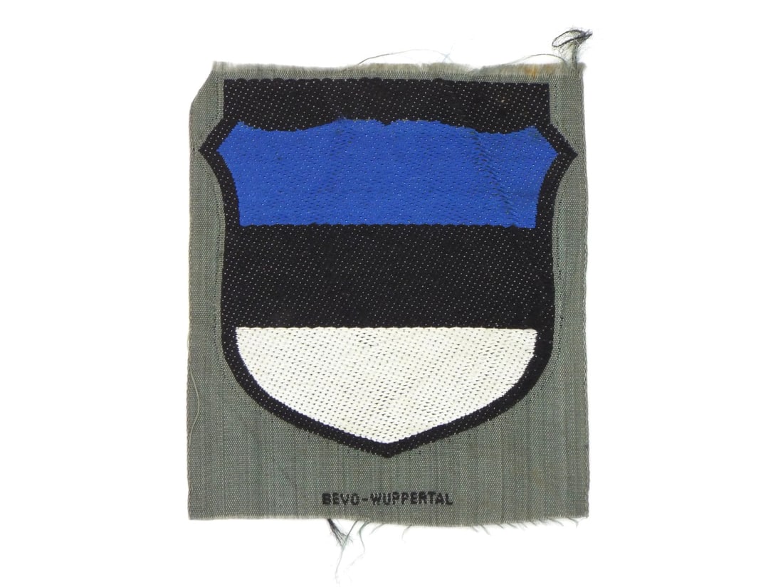 German WWII Estonian SS Volunteer Sleeve Shield: German WWII Estonian SS volunteer sleeve shield patch constructed from BeVo pattern woven rayon thread over grey backing cloth. Obverse shows crisp Estonian tricolor shield in blue, black and white wi