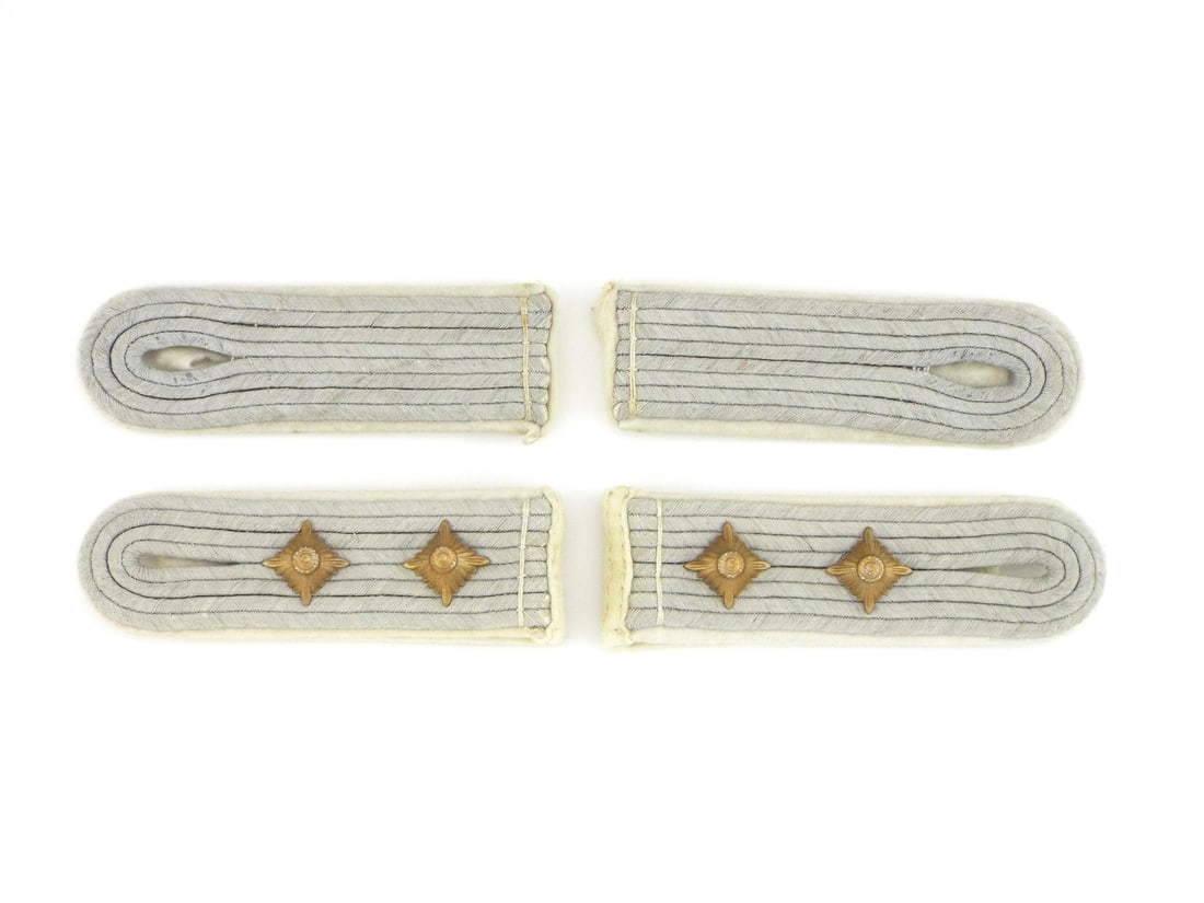 Two Sets of German WWII INFANTRY OFFICER Shoulder Boards: Pair of slip on shoulder straps featuring matte silver grey braid mounted on white wool branch piping. Captain boards exhibit two gilt rank pips with mild surface tarnish. Reverse retain felt wool att