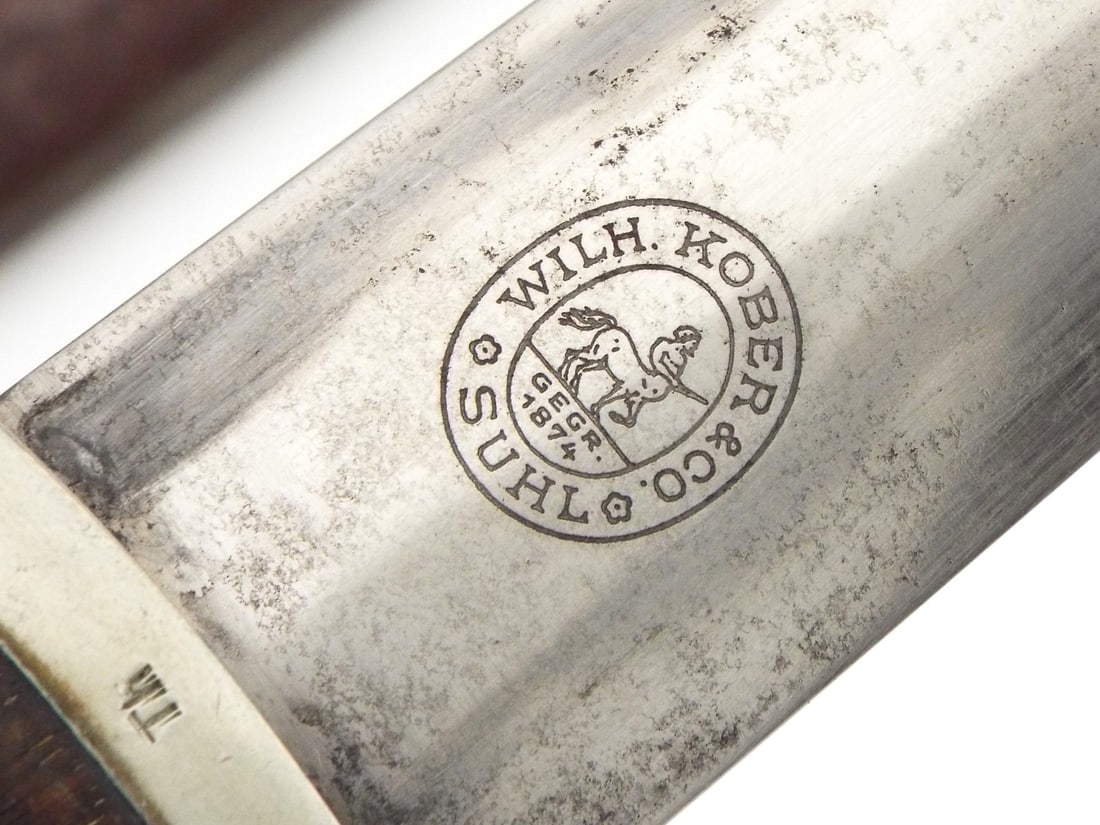 RARE MAKER German WWII SA Dagger By WILHELM KOBER: Double edged steel blade showing age tarnishing and light surface wear featuring the etched regional motto translating to Everything for Germany on the obverse alongside the maker's logo on the revers