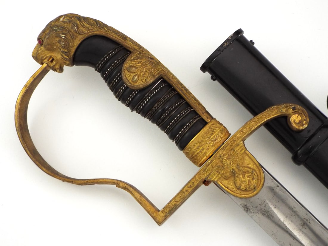 German WWII Army Officer Lion Head Sword By WKC with WWI BLADE: Imperial period single edge polished blade exhibits light surface handling marks and bears dual king and knight helmet mark on ricasso under langet. Gilded brass hilt features high relief Wehrmacht ea