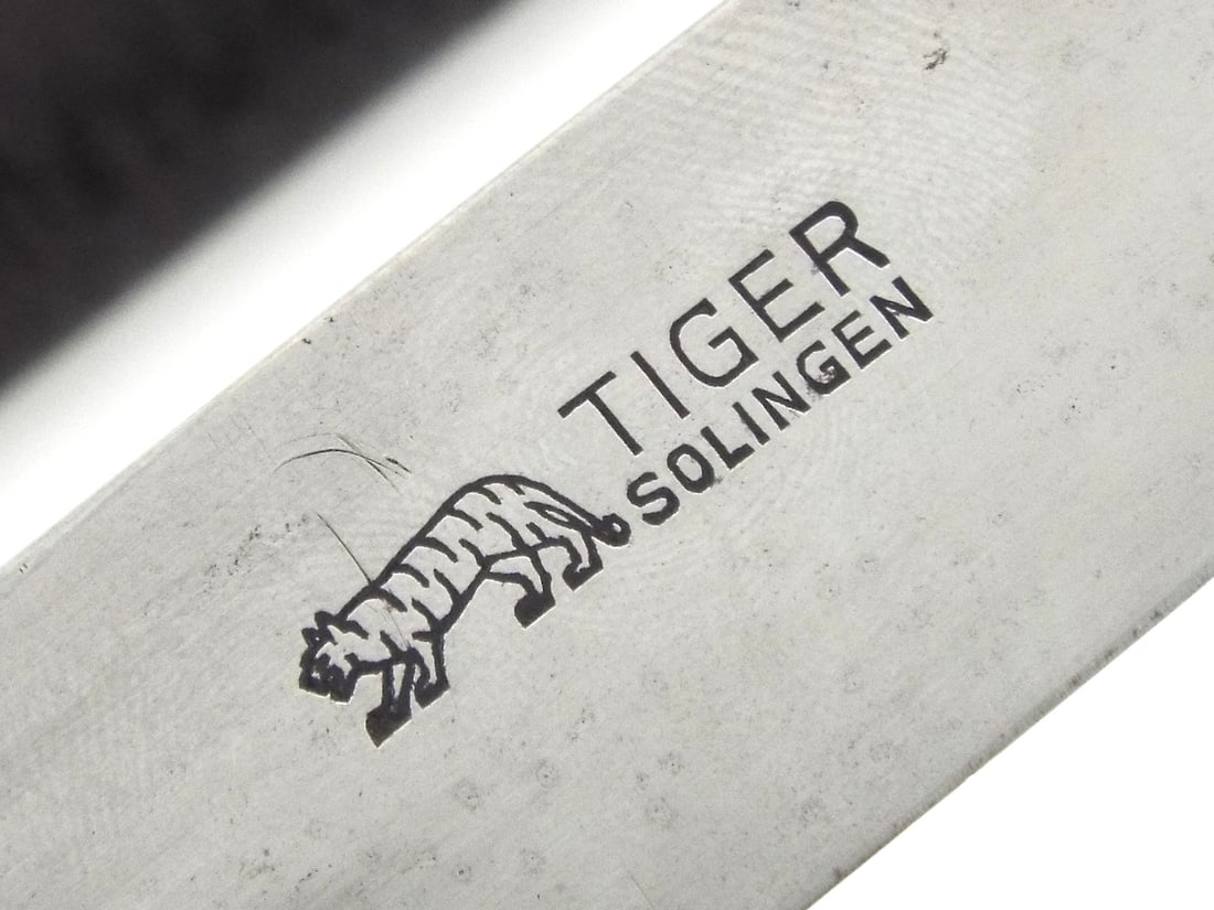 Early German WWII HJ Knife RZM M7/68 By TIGER SOLINGEN: This example exhibits a spear point blade displaying honest wear, prominently stamped with the TIGER SOLINGEN trademark and RZM M7/68 contract codes. The hilt features checkered composite grips housin