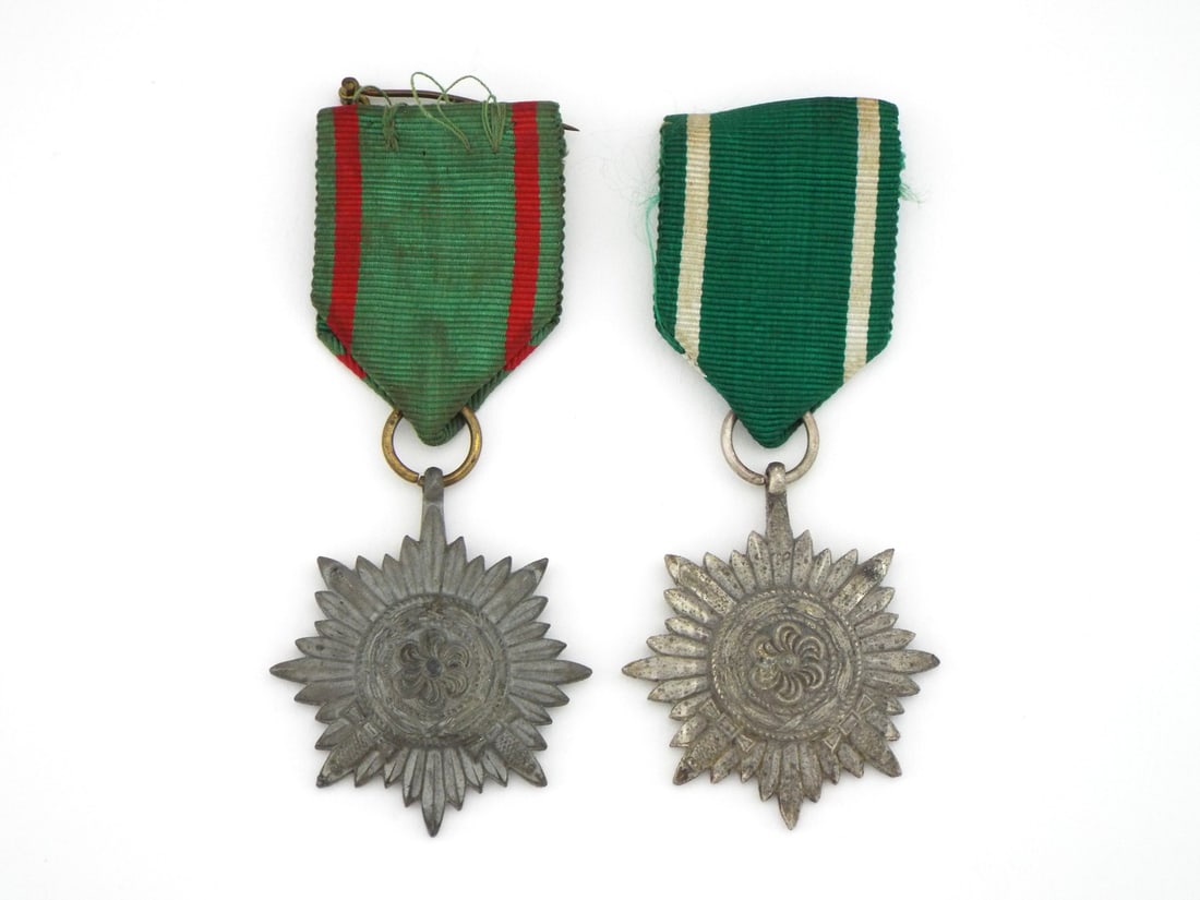 Pair of German WWII Ostvolk EASTERN PEOPLE'S Medals: Eight pointed starburst planchets feature central rosette motifs enveloped by laurel wreaths with integrated crossed swords indicating gallantry in combat. Zinc construction exhibits uniform patinatio