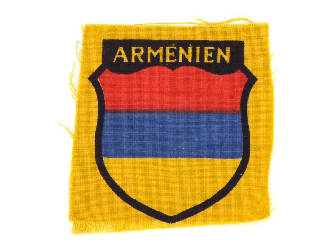 German WWII ARMENIAN VOLUNTEER LEGION Insignia Patch: German WWII printed canvas sleeve shield patch features three color national tricolor heraldic shield graphics in red, blue and yellow with top text translation reads Armenia. Canvas body shows light 
