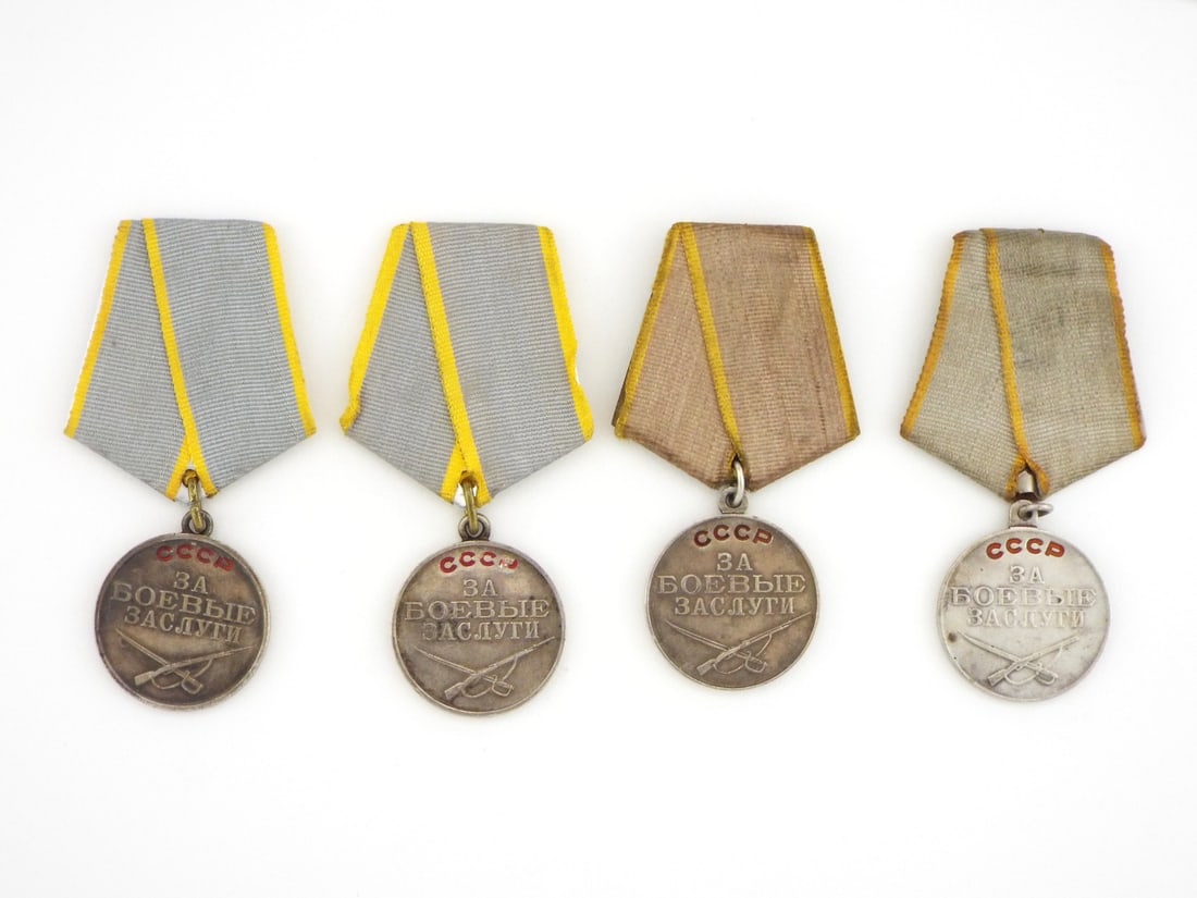 Soviet WWII Era Medals For Battle Merit Silver Group: Four silver campaign medals display raised Cyrillic legend and crossed weaponry over varied patination from bright luster to deep toning, mounted on five sided yellow bordered ribbons, includes two WW