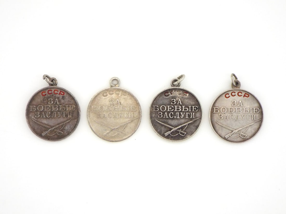 Soviet WWII Era Four Combat Merit Medals In Silver & Enamel: Lot of four circular silver planchets featuring relief USSR lettering with preserved red enamel, central Russian inscriptions reading For Combat Merit, crossed rifles and broadswords over planchets di