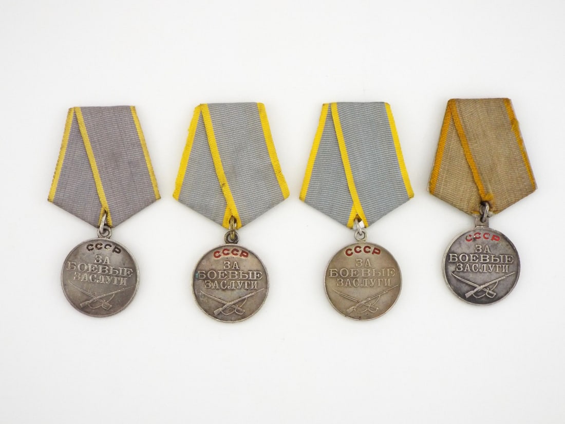 Soviet WWII Era Four Medals USSR For Combat Merit In SILVER: Collection of four USSR Medal For Combat Merit features silver planchets displaying crossed rifle and saber motifs beneath red enamelled Cyrillic script. Reverse faces exhibit light surface handling, 