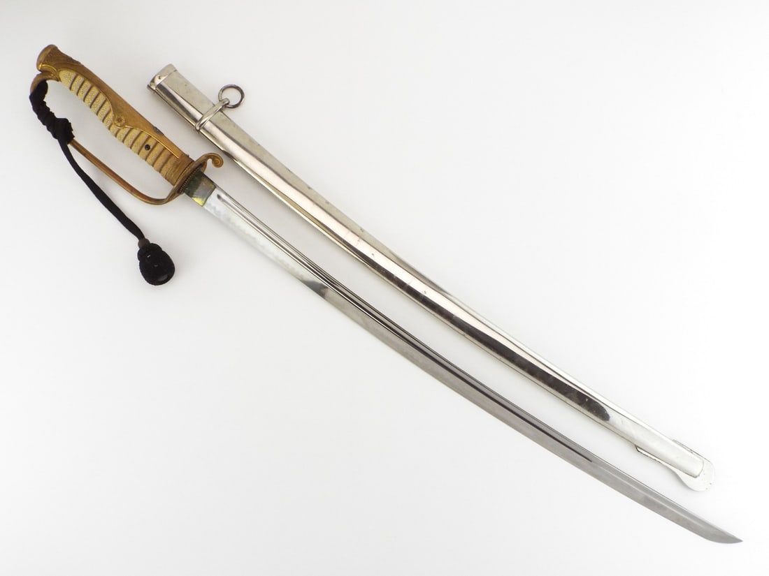 Japanese Meiji Imperial Army Officer Kyu Gunto Sword with Black Knot: Sword featuring single edged curved blade with grayed patina and visible wavy hamon along edge beneath uniform fuller. Brass D-guard hilt retains bright gilding, embellished with pierced cherry