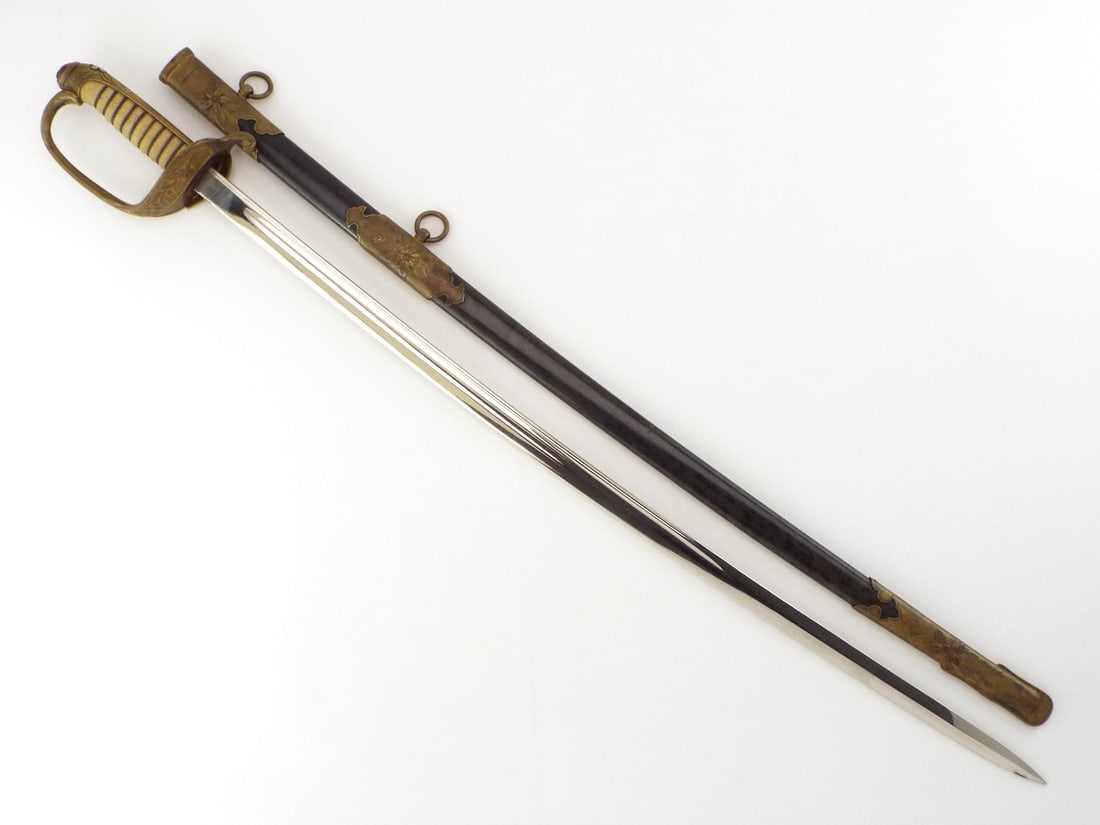 Japanese WWII Naval Officer Sword Complete with Scabbard: Bright single edged steel blade showing mild surface darkening and light runner marks along the fullers. Gilt brass hilt retains strong finish with trace rub wear, featuring detailed sakura motifs on 