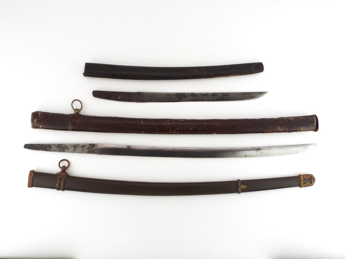 Group of Japanese WWII Mixed Blades & Scabbards: Gunto blade shows polished edge, dark oxidation on unpolished tang with single peg hole, companion short tanto blade exhibits uniform dark patina throughout surface. Unmounted assemblies feature stand
