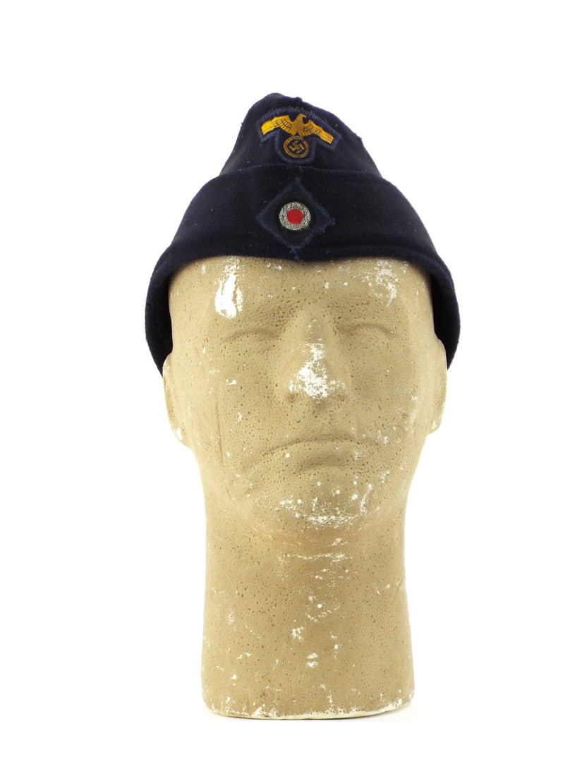 German WWII Naval Overseas Cap by REPEL MUNICH Size 58: Navy blue wool body exhibits light surface tracking and minor moth nips to crown. Golden-yellow machine woven national eagle and cockade remain firmly attached with period zig-zag stitching. Interior 