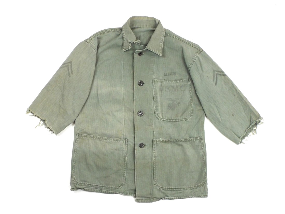 US WWII USMC Utility Jacket with Stenciled Insignia: Herringbone twill body displays age consistent fading, light staining and a field altered cut sleeve modification. Chest pocket features a clear printed Eagle, Globe and Anchor emblem below block lett