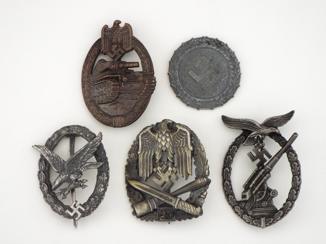 German POST WWII Mixed Badges Lot: Die struck zinc and alloy construction displaying varied surface tarnish and patina. Lot includes Panzer, Flak, pilot, air protection and numbered assault badges with functional vertical pins, wire ca