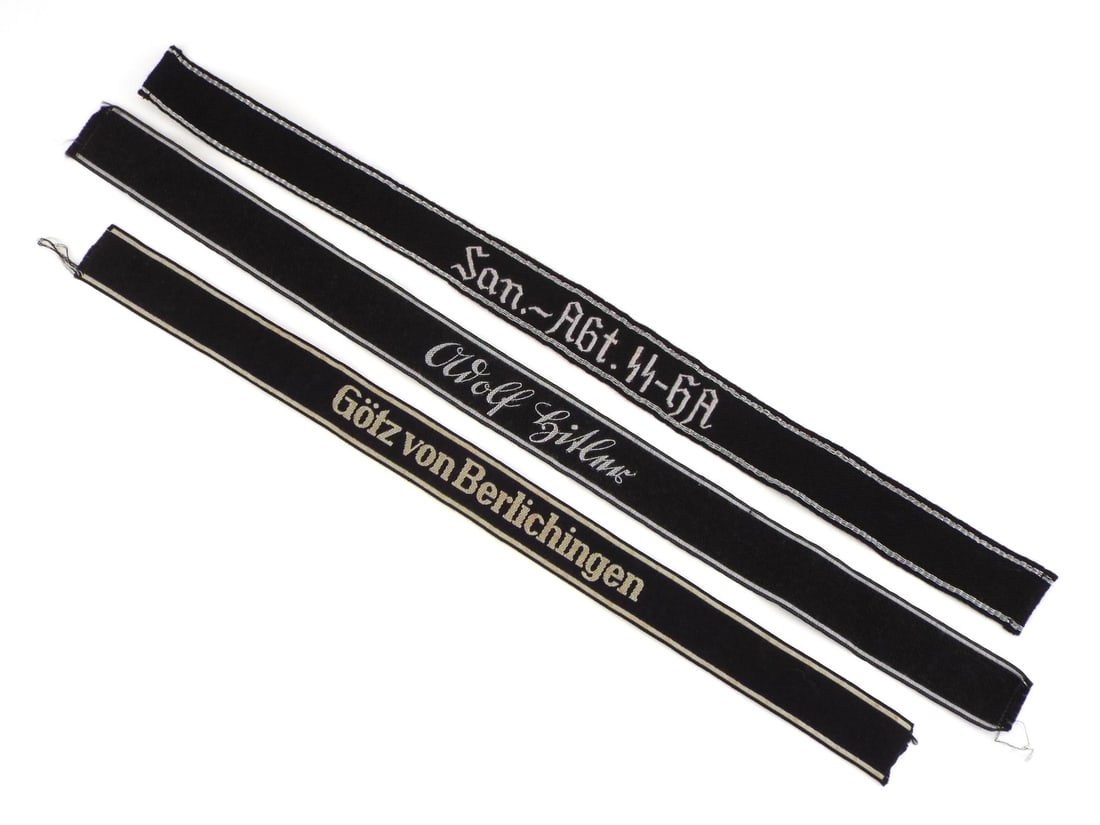 German Post WWII SS Cuff Titles with RZM Tag: Cloth band set features black woven wool construction, machine embroidered gothic script reading Medical Detachment SS-GA, woven division name reading Gotz von Berlichingen and cursive script reading 