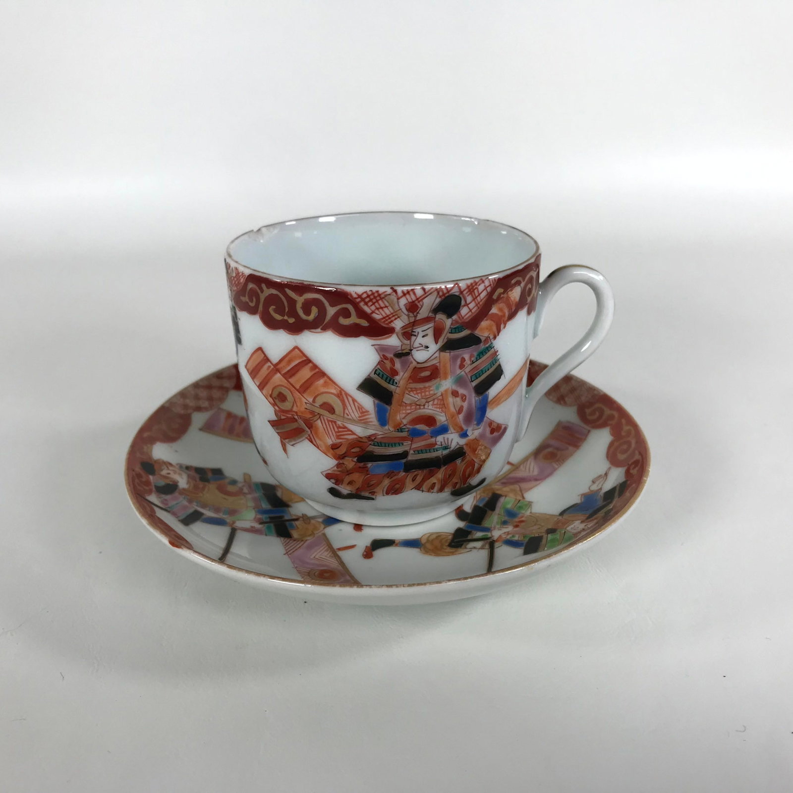 18-19th Century Asian Samuri Teacup and Saucer: Cup measures 2 1/4" tall, 3 3/8" wide. Underplate is 4 3/4" wide. Please note, teacup is chipped.