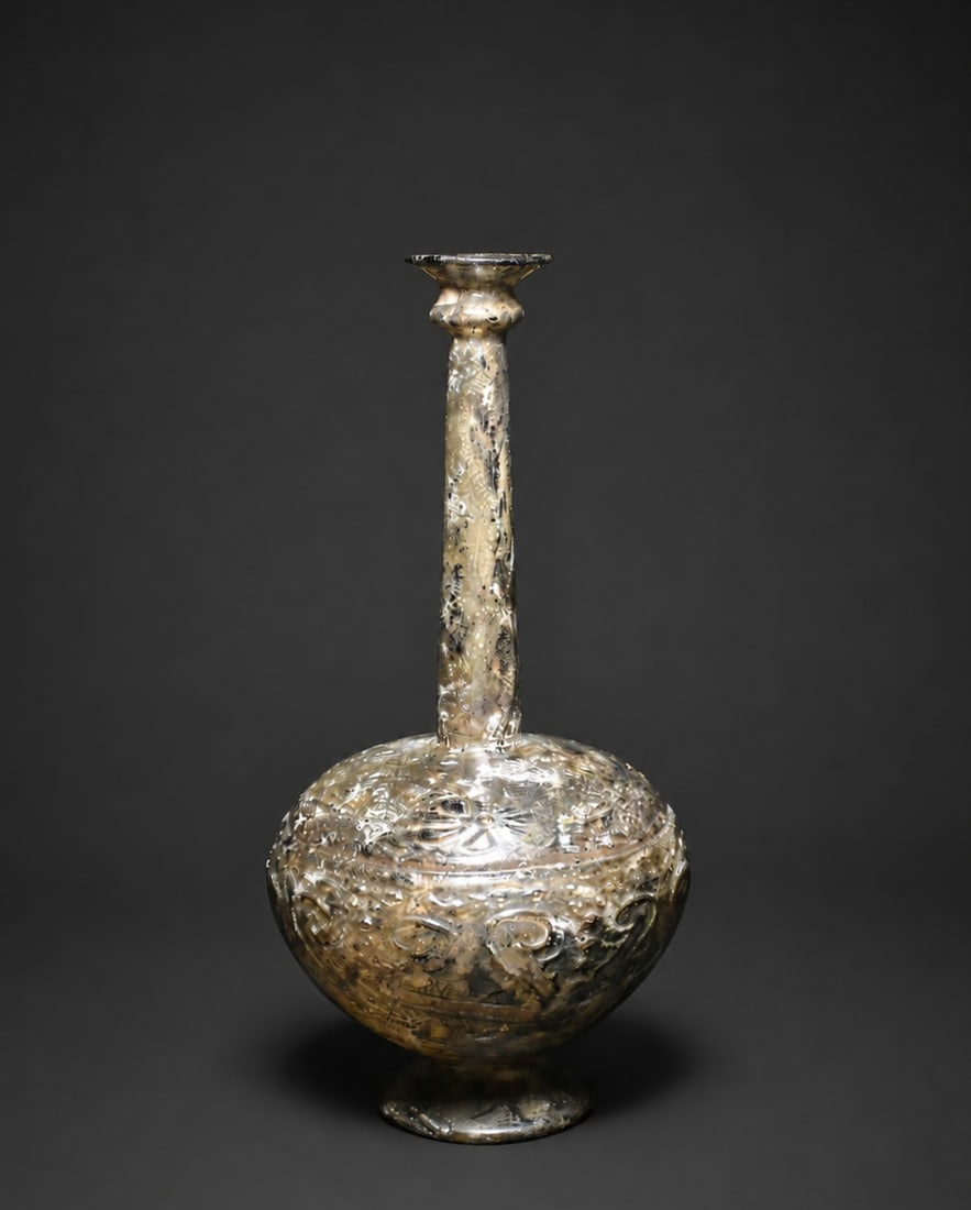 An islamic long neck blown glass bottle, 9thC persia: A rare Islamic blown glass long-neck bottle, Persia, 9th century CE. Of elegant globular form with a tall cylindrical neck, the body richly decorated with intricate raised and wheel-cut style patterns