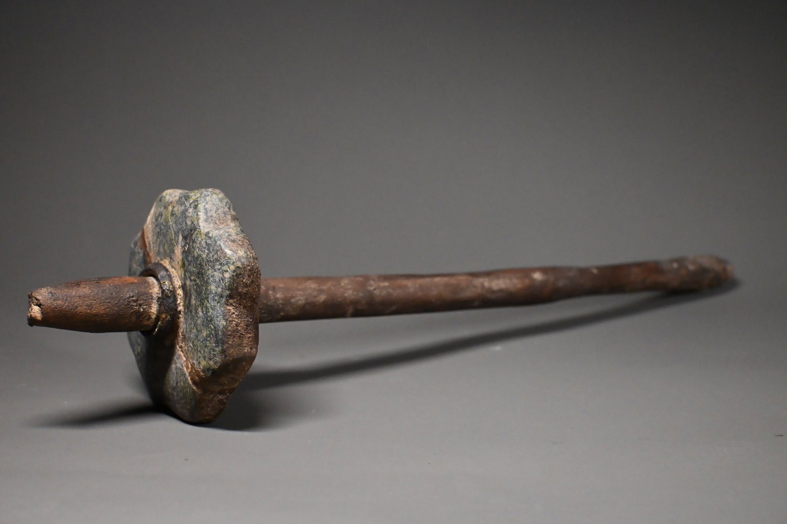 An egyptian wooden mace or weapon: Ancient Egyptian stone mace with original wooden haft, featuring a lobed grey-green stone macehead mounted on a long tapered wooden shaft. Weapons of this type served both military and ceremonial purp
