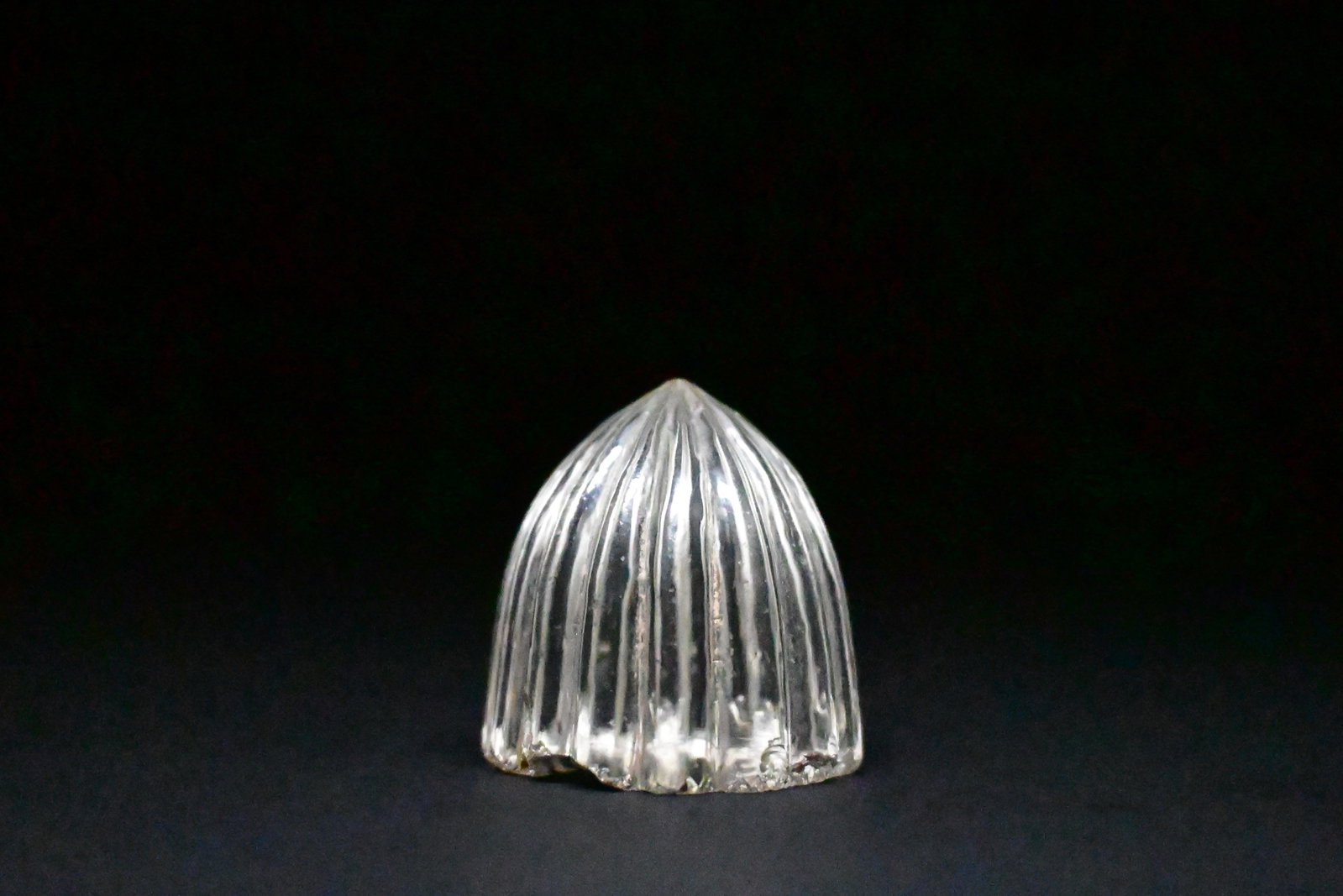 An early-islamic glass or rock crystal game piece: An Early Islamic Glass / Rock Crystal Gaming PieceNear East or Persia, circa 8th–11th century CE. 3.3cm heightFinely carved in a domed form with vertically ribbed sides tapering to a pointed apex, t