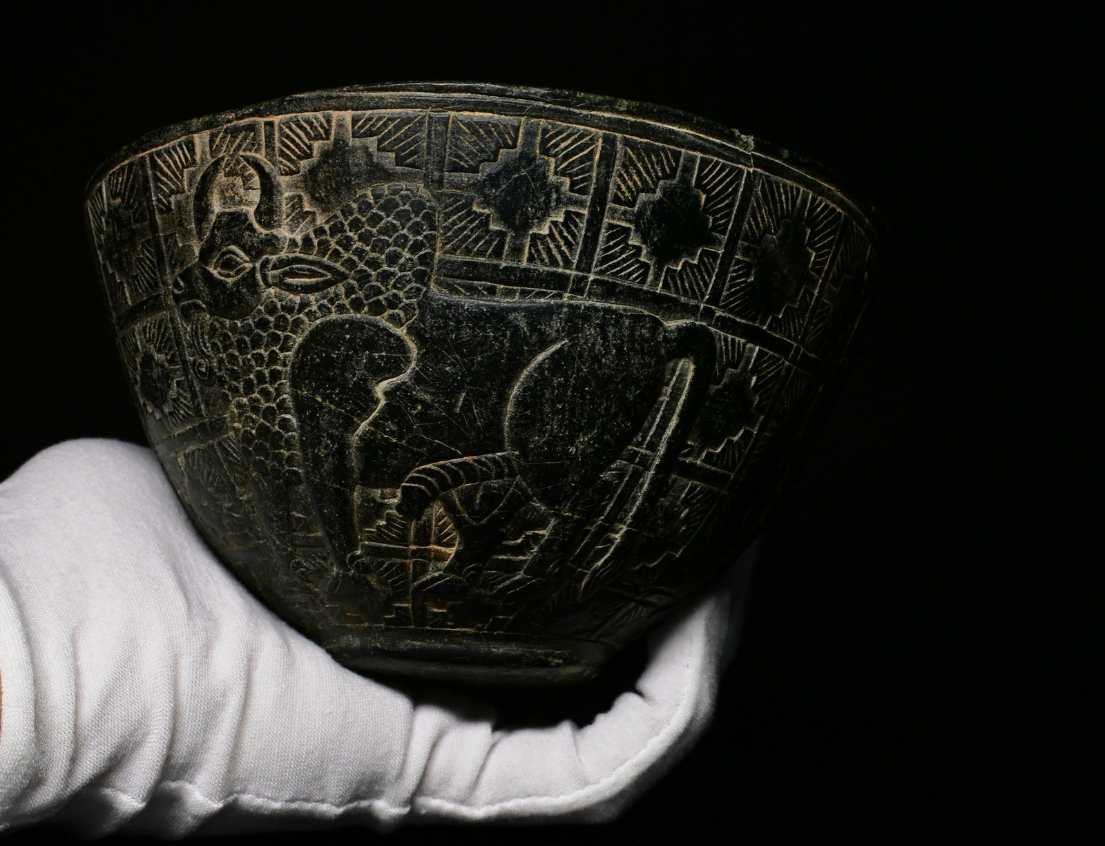 A bactrian bowl with zebu bulls: Ancient bactrian chlorite bowl with bulls, 2-3rd millenium BC. Finely carved from a dark grey to black steatite stone, this elegant hemispherical vessel stands on a circular foot with a surrounding ba