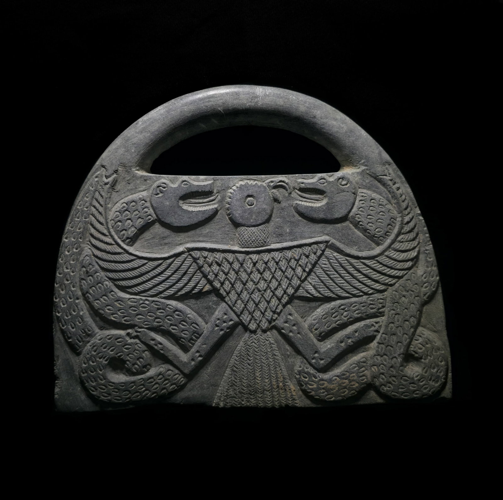 An important bactrian stone bag: An important and rare bactiran/jiroft stone purse/bag, 2nd-3rd millenium BC.The body is engraved on one side with an eagle fighting two dragon-serpents. On the other side, two entwined