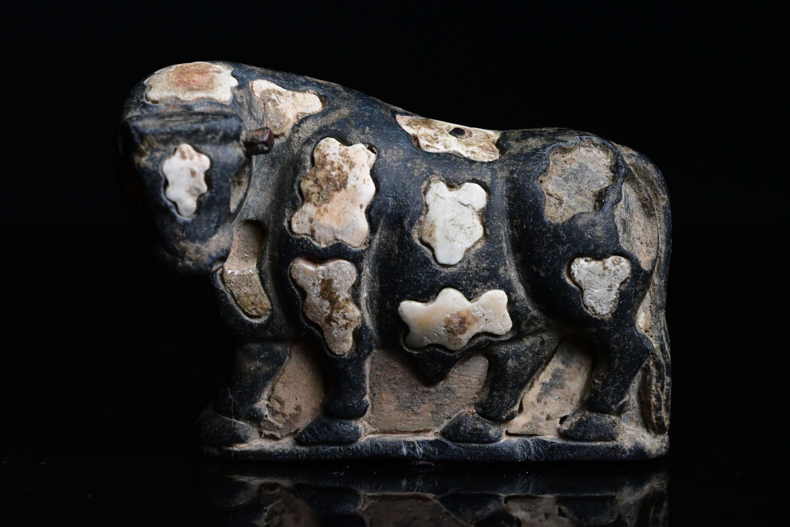 A Bactrian Bull Statue: Bactria–Margiana Archaeological Complex (BMAC) Bull FigurineCentral Asia, ca. 2300–1700 BC.A finely carved stone bull depicted with a robust body and lowered head. The figure is decorated with dis