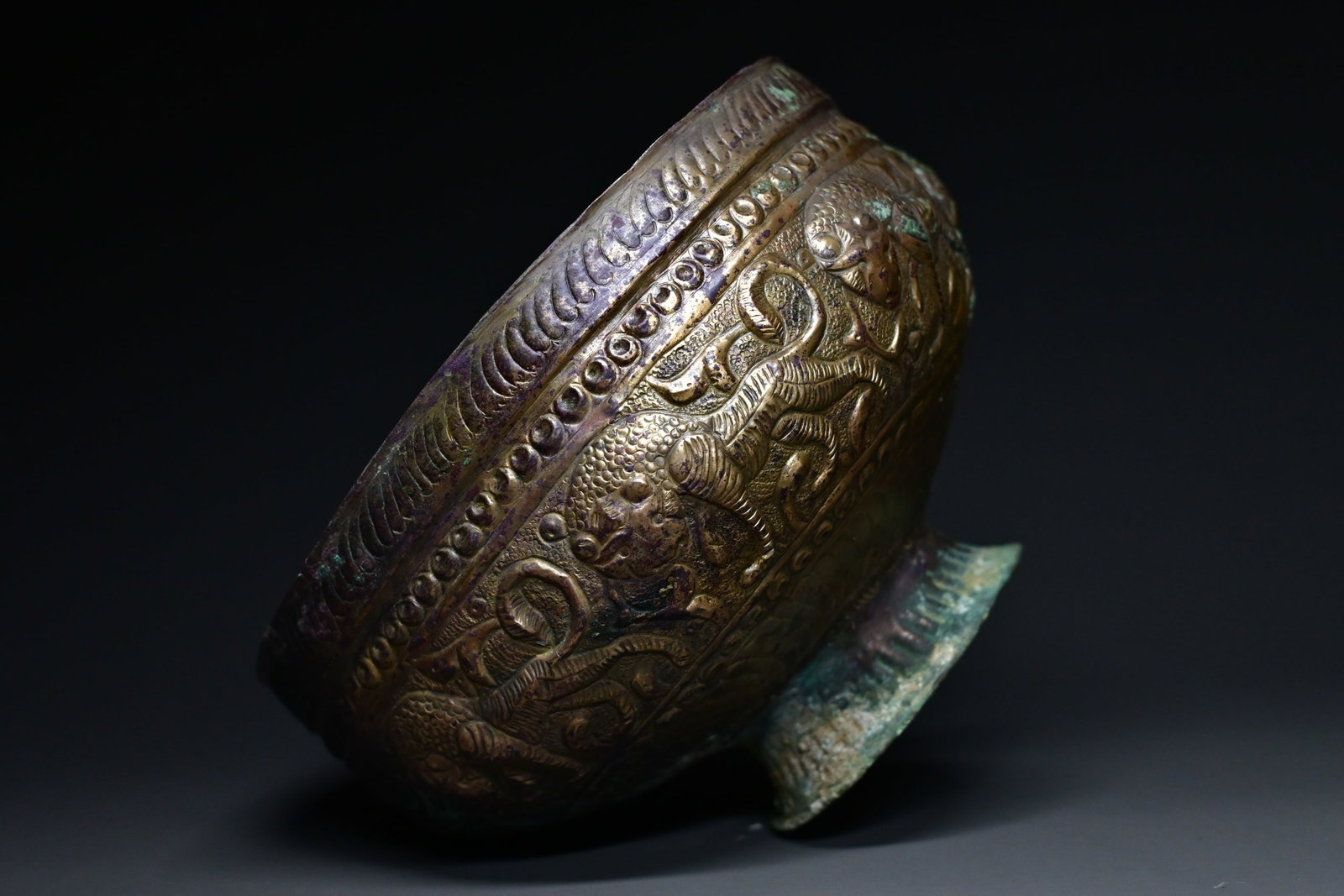 A khorasan repoussé Bronze bowl: Khorasan Repoussé Bronze BowlPersia, 11th–12th Century CEA finely worked Khorasan repoussé bronze bowl, raised on a short foot and decorated with a continuous frieze of eight lions separated by sc
