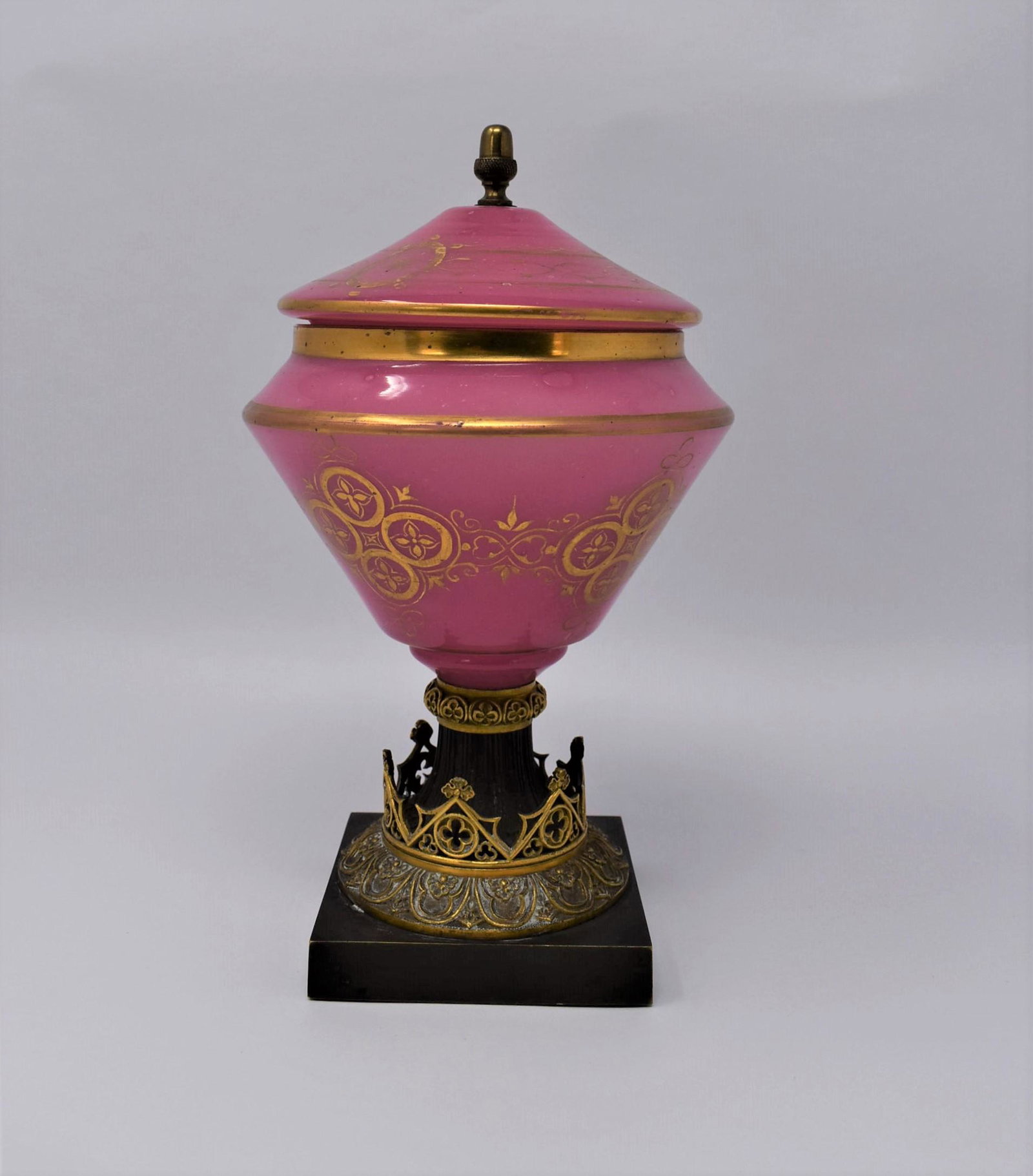 Antique French gothic revival opaline glass bombonniere: An unusual gilt decorated pink opaline glass bombonniere and cover on a gilt and patinated gothic style bronze base. France, circa 1860. Un-marked. Approximate measurements: 9"H x 5" in diameter