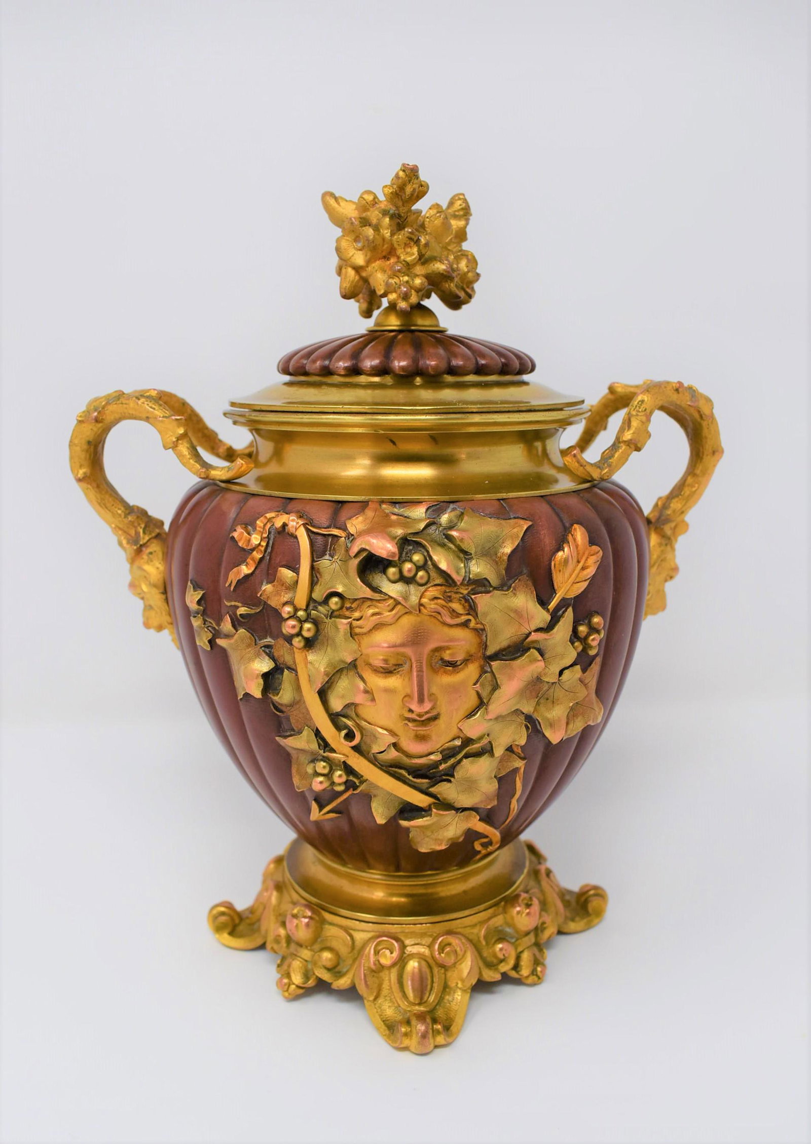 Antique French ormolu and red patinated bronze covered urn: An unusual antique French ormolu gilt bronze and red patinated bronze covered urn with a lobed boddy, and a central figural medalion gilt with two tone gold. Very nicely made.Apparently un-marked. App
