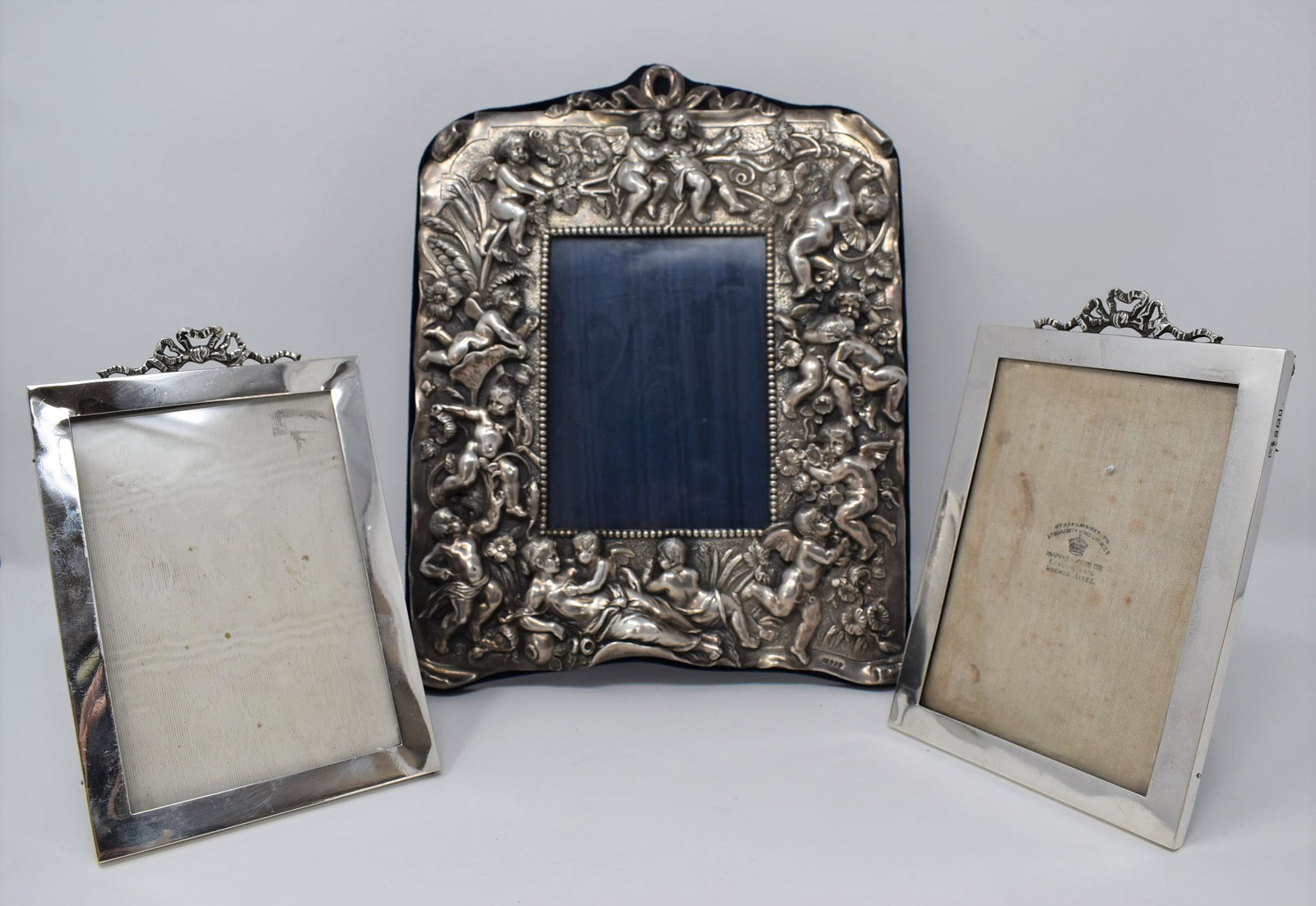 Three English sterling silver easel back frames: A group of three antique sterling silver easel back frames including a single embossed silver easel back picture frame with decor of flolicking putti with un-identified marks ( possibly city of Dublin