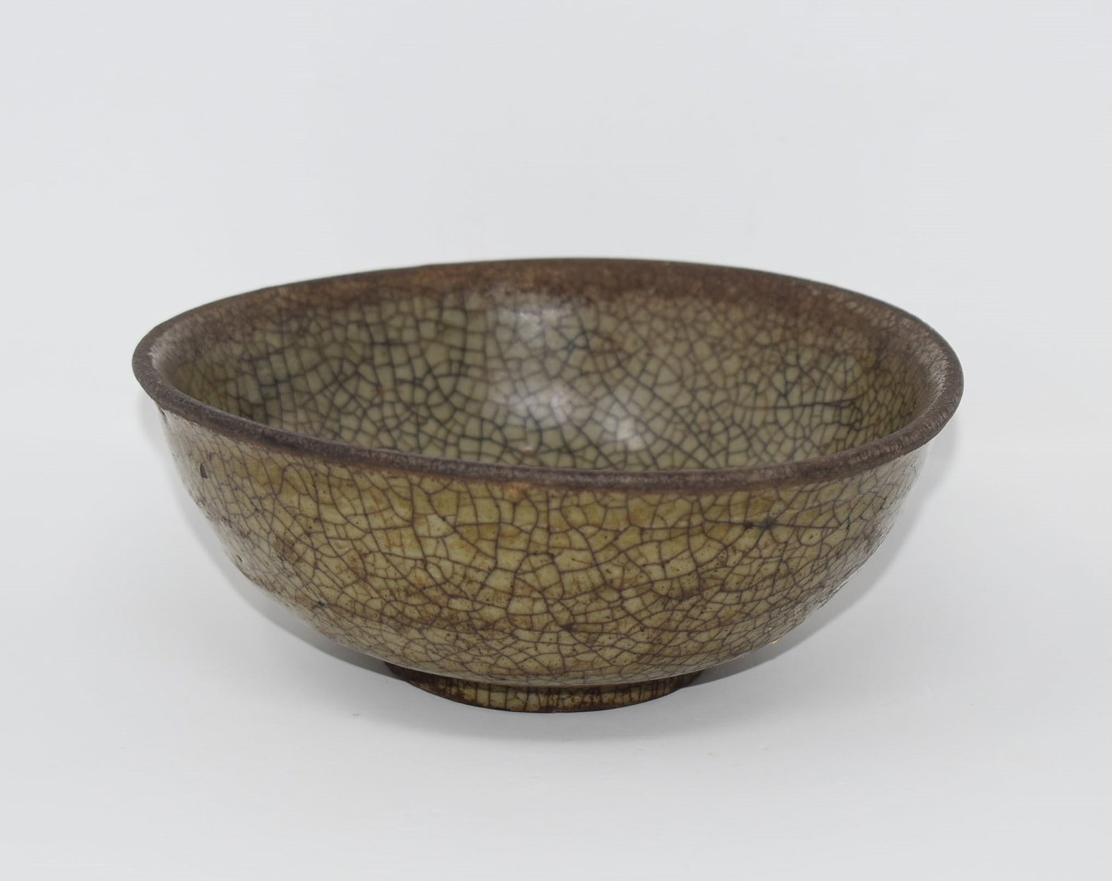 A antique Chinese celadon glazed bowl: An antique Chinese celadon glazed bowl with crackled glaze. The glaze "olive" hued. From the Maria Anglesio collection, thence by descent to the present owner. Approximate measurements: 2.5"H x 6.25"