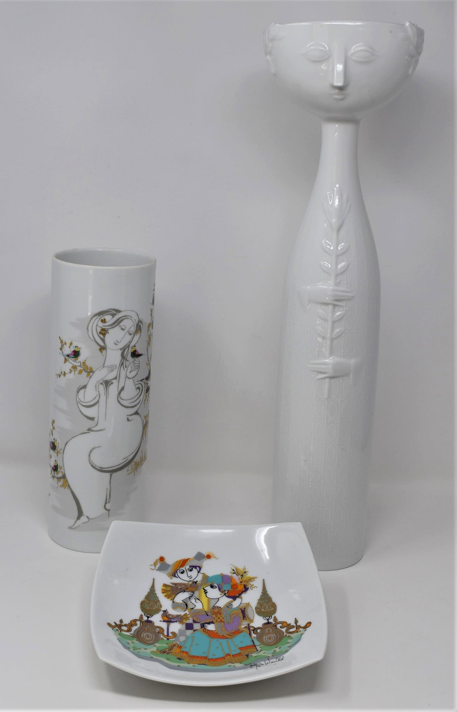 A grouping of three Bjorn Wiinblad for Rosenthal porcelain items: A grouping of three Bjorn Wiinblad for Rosenthal porcelain items including a tall " face" vase (18.5" tall x 5"W x 4.5"D)a cylindrical vase ( 10.25"H x 3.5" in diameter) and a square dish ( 1.5"h x 7"