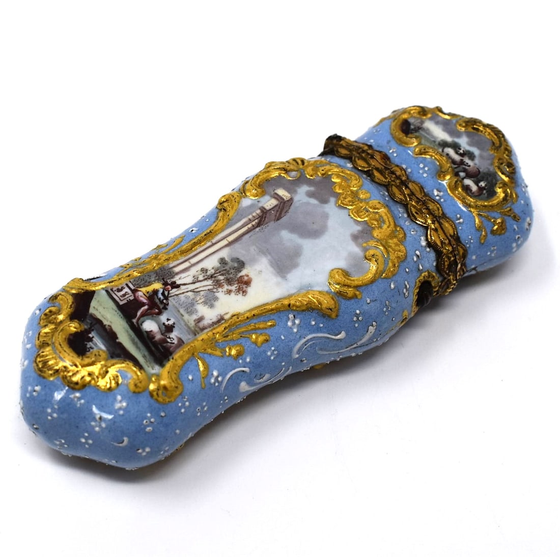 A South Staffordshire enamel etui with blue ground, circa 1770: A South Staffordshire enamel etui, circa 1770 of rococo form with light relief-moulded scrolled panels, the hinged gilt metal-mounted cover opening to reveal a penknife and tweezers, the panels delica
