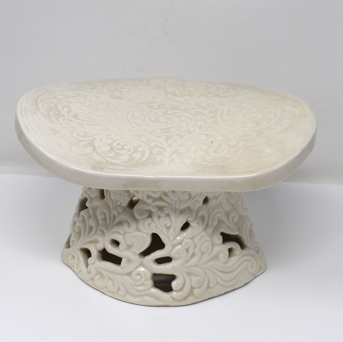 A Chinese white-glazed porcelain pillow: An Chinese ivory white glazed porcelain pillow with reticula Approximate measurements:ted foliate base and carved foliate motifs on the head support. 51/2"h x 9"W x 7"D or 14cm H x 22.7cmW x 17.7cm D