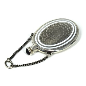 An antique silver and enamel perfume bottle on chain