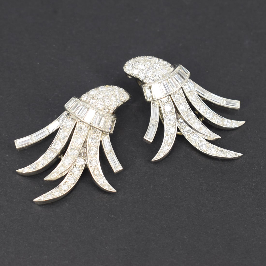 A pair of platimum and diamond spray earrings: A pair of platinum and diamond spray-form earrings with 14kt white gold clip-on earring backings. Each individual earring is comprised of 14 diamond baguettes, and 44 round full and single cut diamond