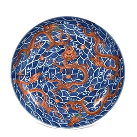 A massive Chinese Qing dynasty iron-red and underglaze blue 'nine-dragon' charger