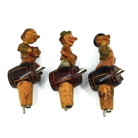 A group of three German carved wood bottle stoppers