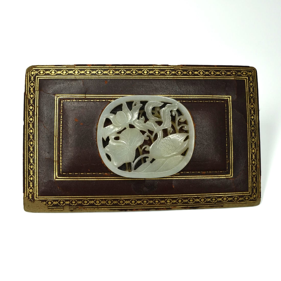 A Chinese pale celadon circular reticulated plaque: A Chinese pale celadon circular reticulated plaque featuring a duck swimming among lotus flowers. Glued to a leather box cover was the previous owners. Approximate measurements ( plaque only): 2 3/4"W