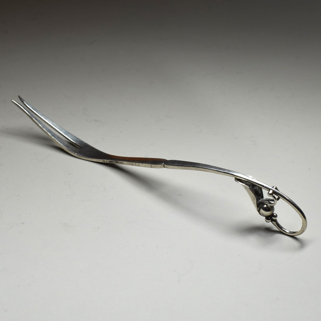 A GEORG JENSEN sterling silver 'Ornamental' #21 cold cut / buffet fork: A Georg Jensen 'Ornamental' #21 cold cut or buffet sterling silver fork, the handle featuring an elegant floral "peapod" motif. Weight: 0.94 troy Oz or 29.23g Approximate measurements: 7 1/4"L or 18.4
