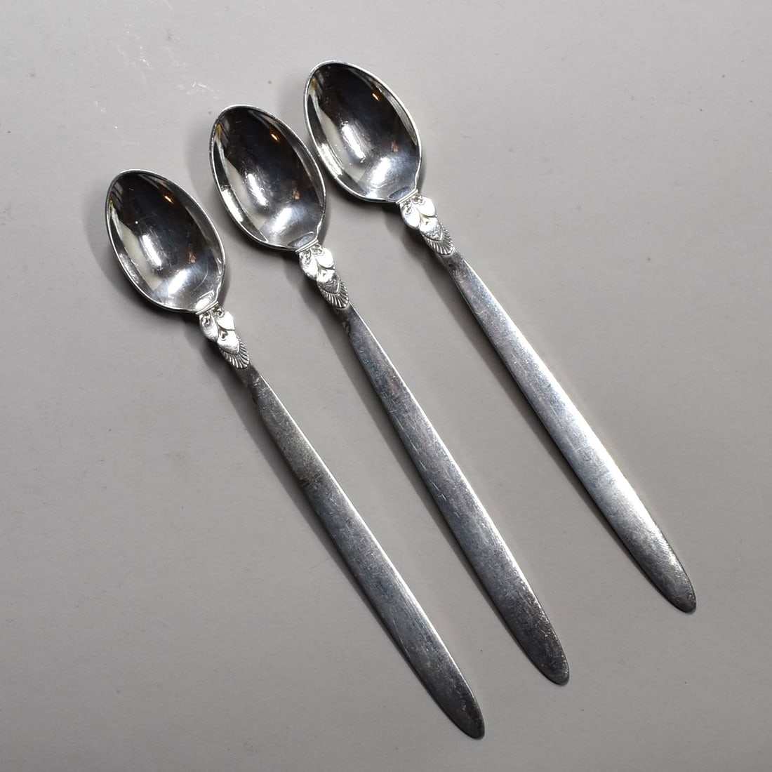 A grouping of three GEORG JENSEN sterling silver 'Cactus' pattern Iced Tea spoons: A grouping of three Georg Jensen sterling silver 'Cactus' pattern Iced Tea spoons. This Art Deco pattern was designed by Gundorph Albertus in 1930. With Georg Jensen sterling silver hallmarks 1945-pre