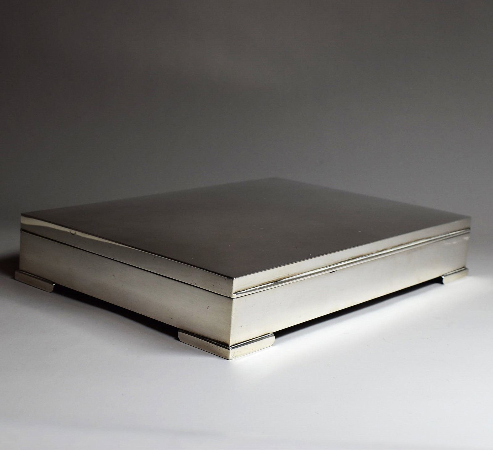 A large Art Deco sterling silver cigar box: A large Art Deco sterling silver cigar box, set of four feet, hinged and with fitted wood interior, marked '925' and with unidentified maker's marks. Circa 1930. Gross weight: 34.48 troy Oz or 1072.7g