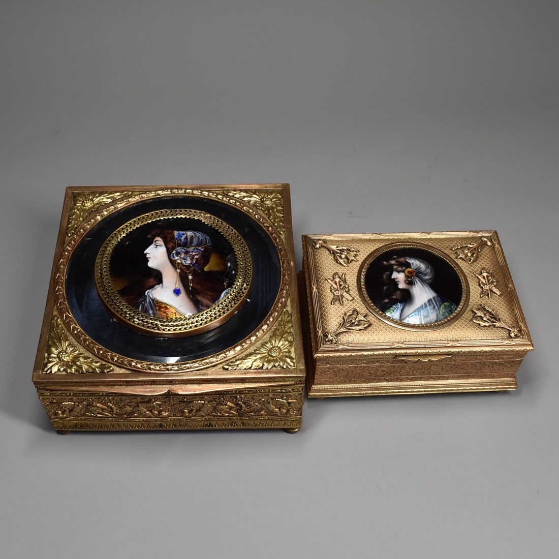 Two antique French gilt brass and enamel dresser boxes: A grouping of two antique French gilt brass and enamel dresser boxes / jewelry boxes circa 1900. The largest box with bevelled glass on the lid and a circular hand painted enamel on copper plaque feat