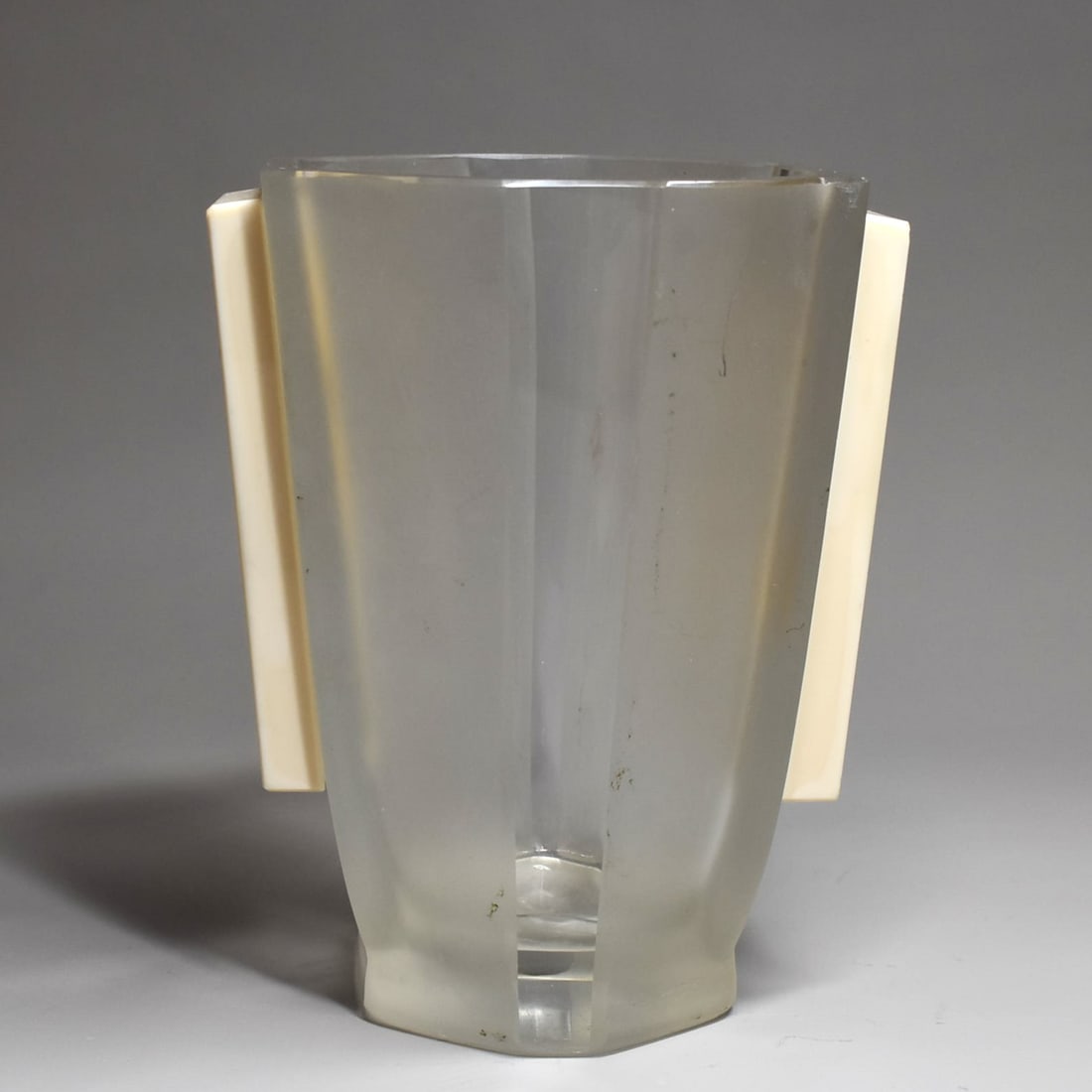 A French(?) Art Deco frosted glass and bakelite vase circa 1935: An unusual faceted and frosted glass French (?) Art Deco vase with applied cream-colored openwork bakelite handles featuring goddess-like female figures. Apparently un-marked. Maker/manufacturer un-kn